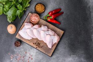 asas de frango cru com ingredientes para cozinhar em uma tábua de madeira