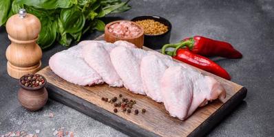 asas de frango cru com ingredientes para cozinhar em uma tábua de madeira