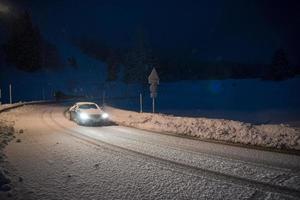 carro dirigindo em estrada perigosa à noite na neve foto