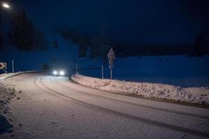 carro dirigindo em estrada perigosa à noite na neve foto