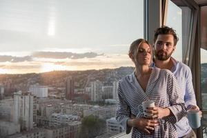 jovem casal desfrutando de café à noite pela janela foto