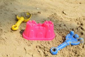 brinquedos de areia de plástico para crianças na praia. Brinquedo de plástico de castelo de areia, brinquedos de plástico de ancinho e pá para crianças. foto