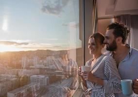 jovem casal desfrutando de café à noite pela janela foto