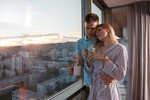 jovem casal desfrutando de café à noite pela janela foto