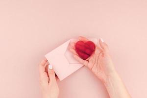 mão de mulher segurando uma pequena carta de amor rosa foto