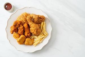 frango frito com batatas fritas e nuggets no prato foto