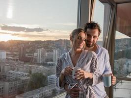 jovem casal desfrutando de café à noite pela janela foto