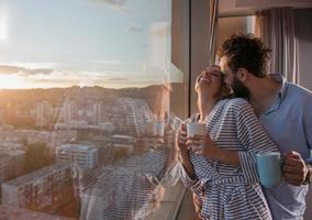 jovem casal desfrutando de café à noite pela janela foto
