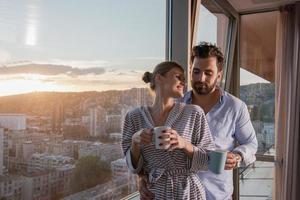 jovem casal desfrutando de café à noite pela janela foto