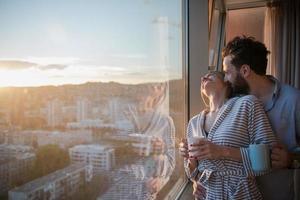 jovem casal desfrutando de café à noite pela janela foto