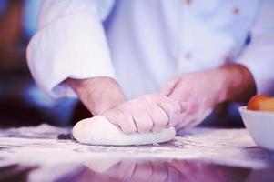 mãos de chef preparando massa para pizza foto