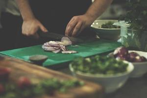 mãos de chef cortando a cebola com faca foto