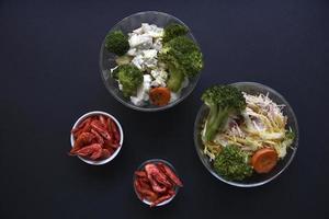 deliciosa salada em uma saladeira de vidro e camarão vermelho em um fundo preto. delicioso café da manhã de salada e camarão. foto