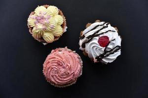 bolos doces com creme e granulado em um fundo preto. deliciosas tortas no café da manhã no preto. foto