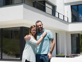 casal se abraçando em frente a nova casa de luxo foto