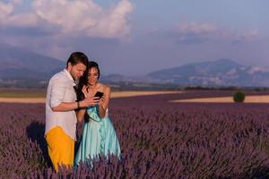 casal no campo de lavanda usando smartphone foto