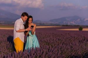 casal no campo de lavanda usando smartphone foto