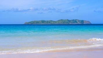 bela praia de areia colorida de ouro incrível com ondas suaves isoladas com céu azul ensolarado. conceito de ideia de turismo calmo tropical, copie o espaço, feche foto