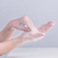 Lavando as mãos. jovem asiática usando sabão líquido para lavar as mãos, conceito de higiene para proteger o coronavírus pandêmico isolado em fundo branco cinza, close-up. foto