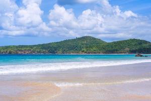 bela praia de areia colorida de ouro incrível com ondas suaves isoladas com céu azul ensolarado. conceito de ideia de turismo calmo tropical, copie o espaço, feche foto