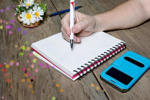 mão humana segurando caneta com caderno aberto foto