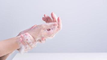 Lavando as mãos. jovem asiática usando sabão líquido para lavar as mãos, conceito de higiene para proteger o coronavírus pandêmico isolado em fundo branco cinza, close-up. foto