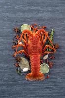 lagosta cozida cozida, deliciosa refeição de frutos do mar jantar com faca e garfo em fundo de ardósia de pedra preta, design de menu de restaurante, vista superior, sobrecarga foto