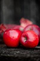 duas maçãs frescas orgânicas vermelhas numa superfície de madeira foto