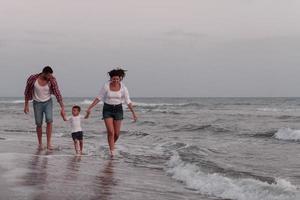 a família aproveita as férias enquanto caminham pela praia com o filho. foco seletivo foto