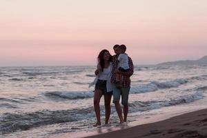 a família aproveita as férias enquanto caminham pela praia com o filho. foco seletivo foto