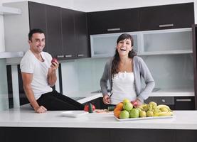 jovem casal se diverte na cozinha moderna foto