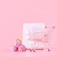 conceito de design de presente de feriado do dia das mães, buquê de flores de cravo rosa com caixa embrulhada isolada em fundo rosa claro, espaço de cópia. foto