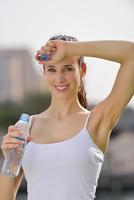 jovem e bela mulher bebendo água após o exercício de fitness foto