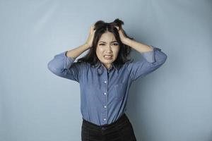 retrato de jovem mulher asiática isolado por fundo azul, sentindo-se frustrado com a expressão do rosto indefeso. foto