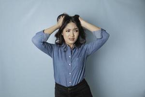 retrato de jovem mulher asiática isolado por fundo azul, sentindo-se frustrado com a expressão do rosto indefeso. foto