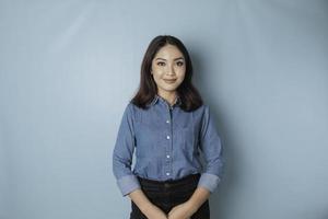 um retrato de uma mulher asiática feliz está sorrindo e vestindo uma camisa azul isolada por um fundo azul foto