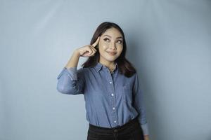 retrato de uma jovem casual pensativa vestindo uma camisa azul, olhando de lado isolado sobre fundo azul foto