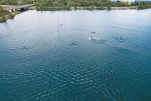 belas imagens da câmera do drone aéreo de willen lake and park, localizado em milton keynes, inglaterra. as pessoas estão desfrutando no lago em um dia quente e ensolarado de verão foto