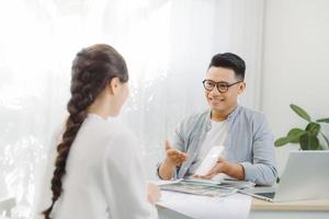 arquiteto masculino e feminino discutindo um conjunto de plantas espalhadas em uma mesa no escritório. foto