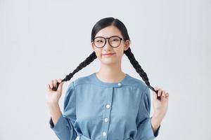 garota encantadora segurando tranças de cabelo nas mãos, câmera de aparência divertida feliz isolada em um fundo branco foto