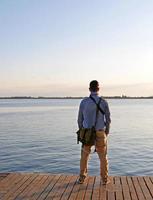 homem olhando para um lago nas horas da tarde foto