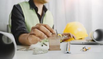 dois colegas discutindo dados de trabalho e tablet, laptop com projeto arquitetônico no canteiro de obras na mesa no escritório foto