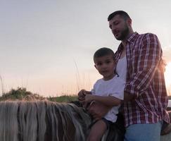 pai e filho gostam de andar a cavalo juntos à beira-mar. foco seletivo foto