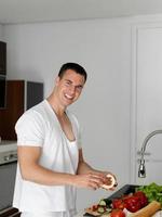 homem cozinhando em casa preparando salada na cozinha foto