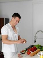 homem cozinhando em casa preparando salada na cozinha foto