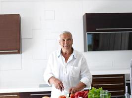 homem cozinhando em casa preparando salada na cozinha foto