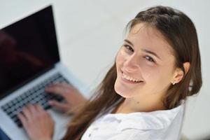 jovem relaxada em casa trabalhando no computador portátil foto