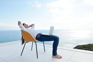 jovem relaxada em casa trabalhando no laptop foto