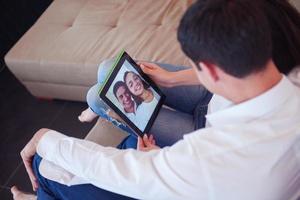 casal em casa moderna usando computador tablet foto