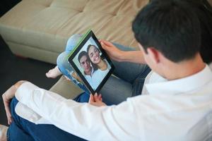 casal em casa moderna usando computador tablet foto